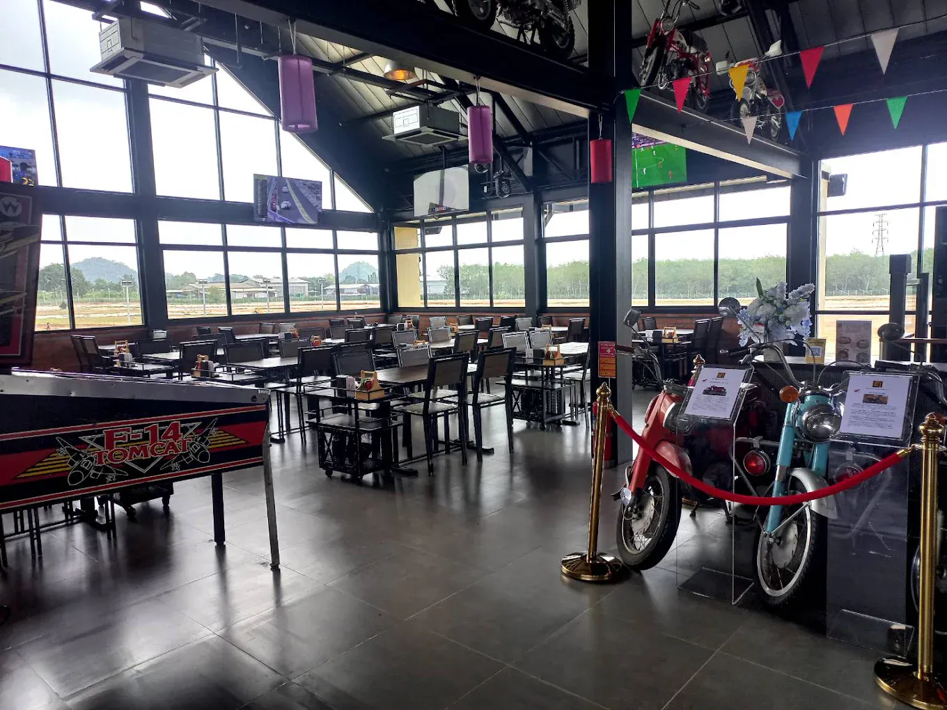 A vintage F-14 Tomcat pinball machine beside placarded classic motorcycles