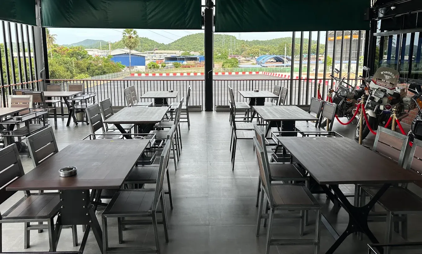 Terrace tables at BOX BOX looking through the railing onto the red-and-white kerbs of the circuit