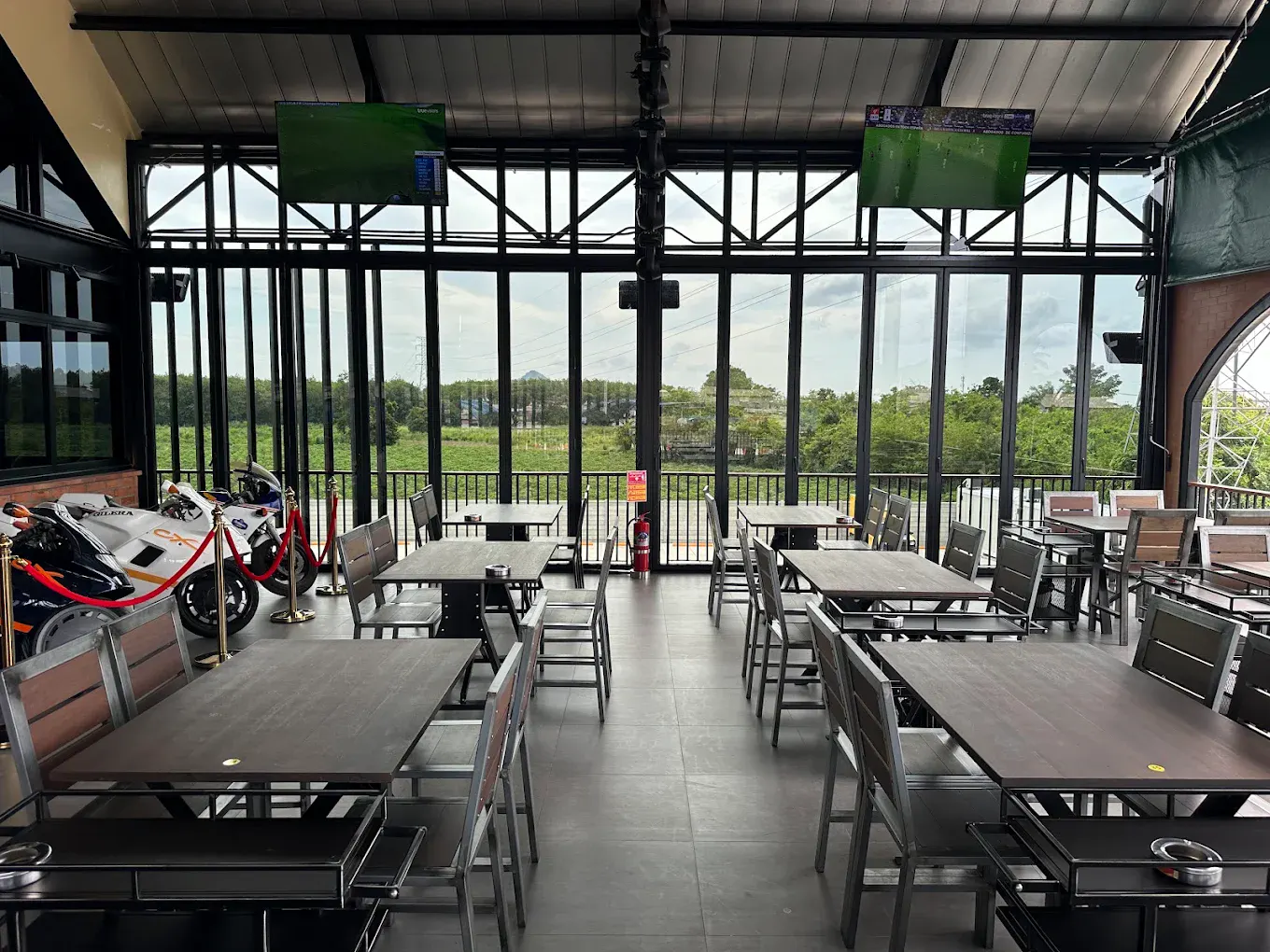 Inside the sports restaurant — tables under the match screens, daylight through the glass wall