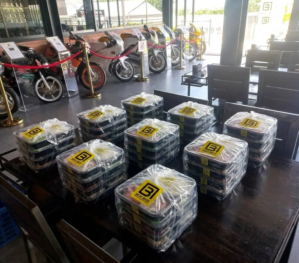 Box Box box-lunch orders on the dining tables, with the Motorbike Gallery’s display bikes behind