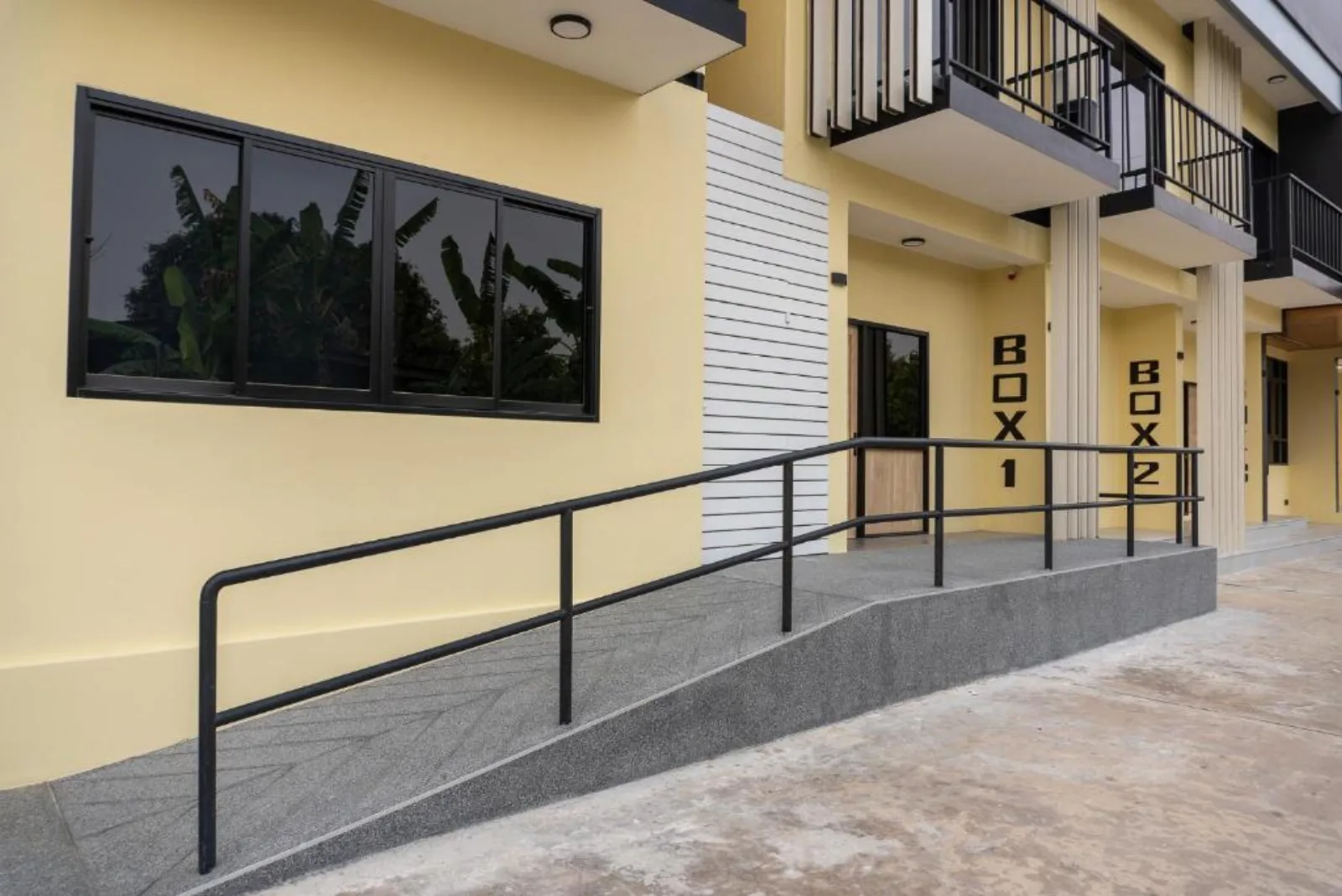 The BOX-numbered façade at Box Box Hotel — rooms marked BOX 1 and BOX 2 along a ramped walkway