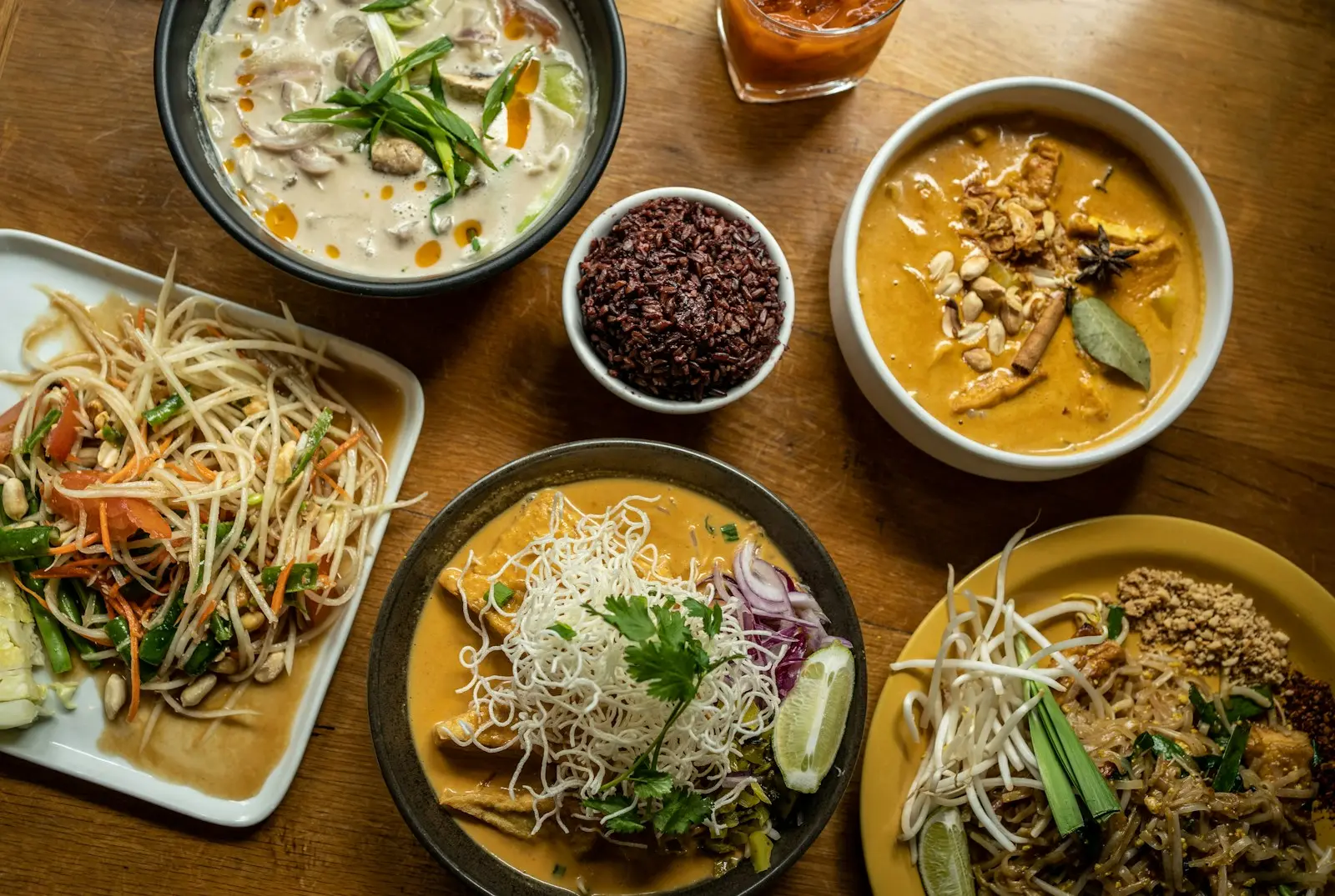 A spread of Thai dishes — som tam, peanut curry and pad thai